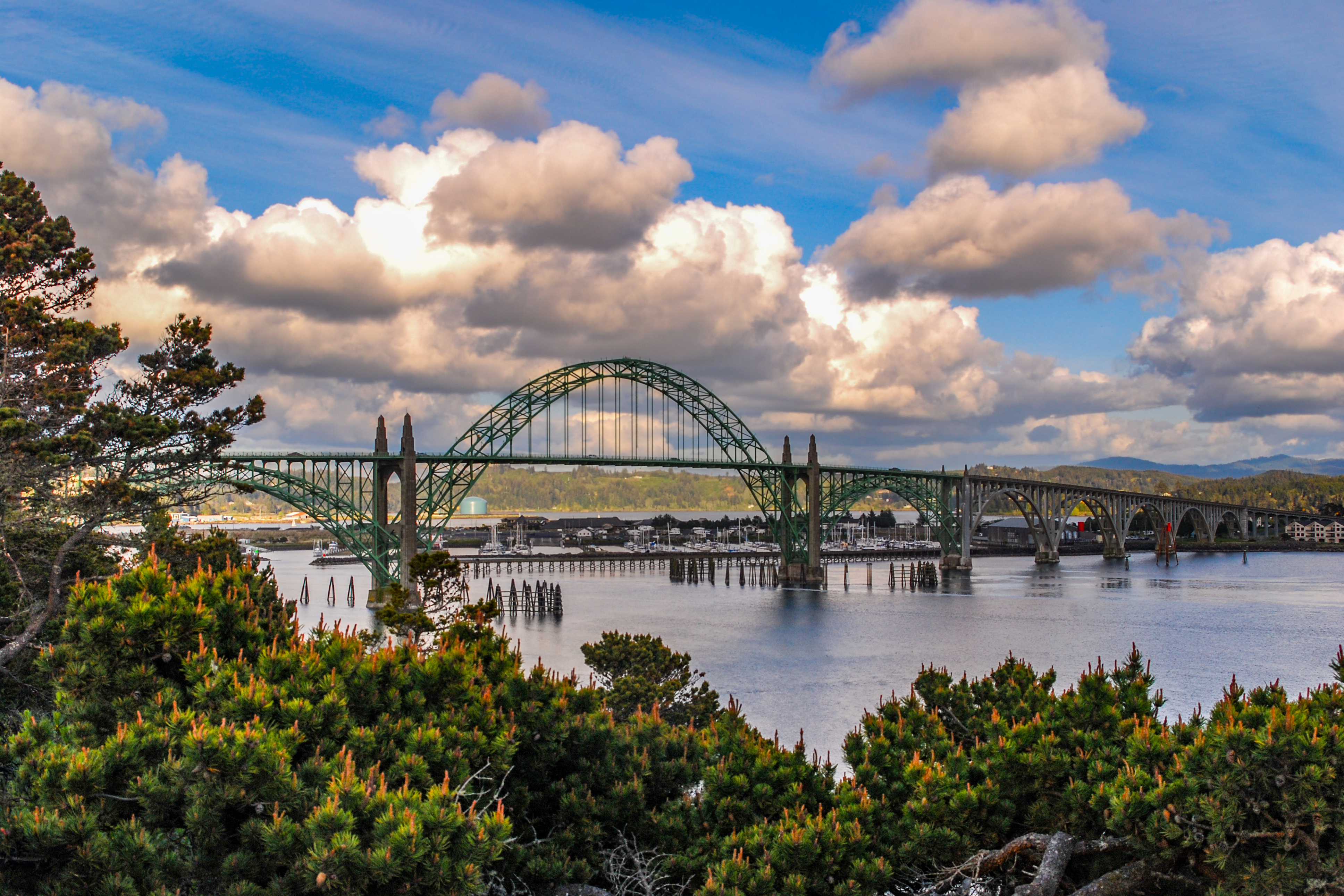 Yaquina Bay Bridge spanning across the water with dramatic clouds above and behind the structure